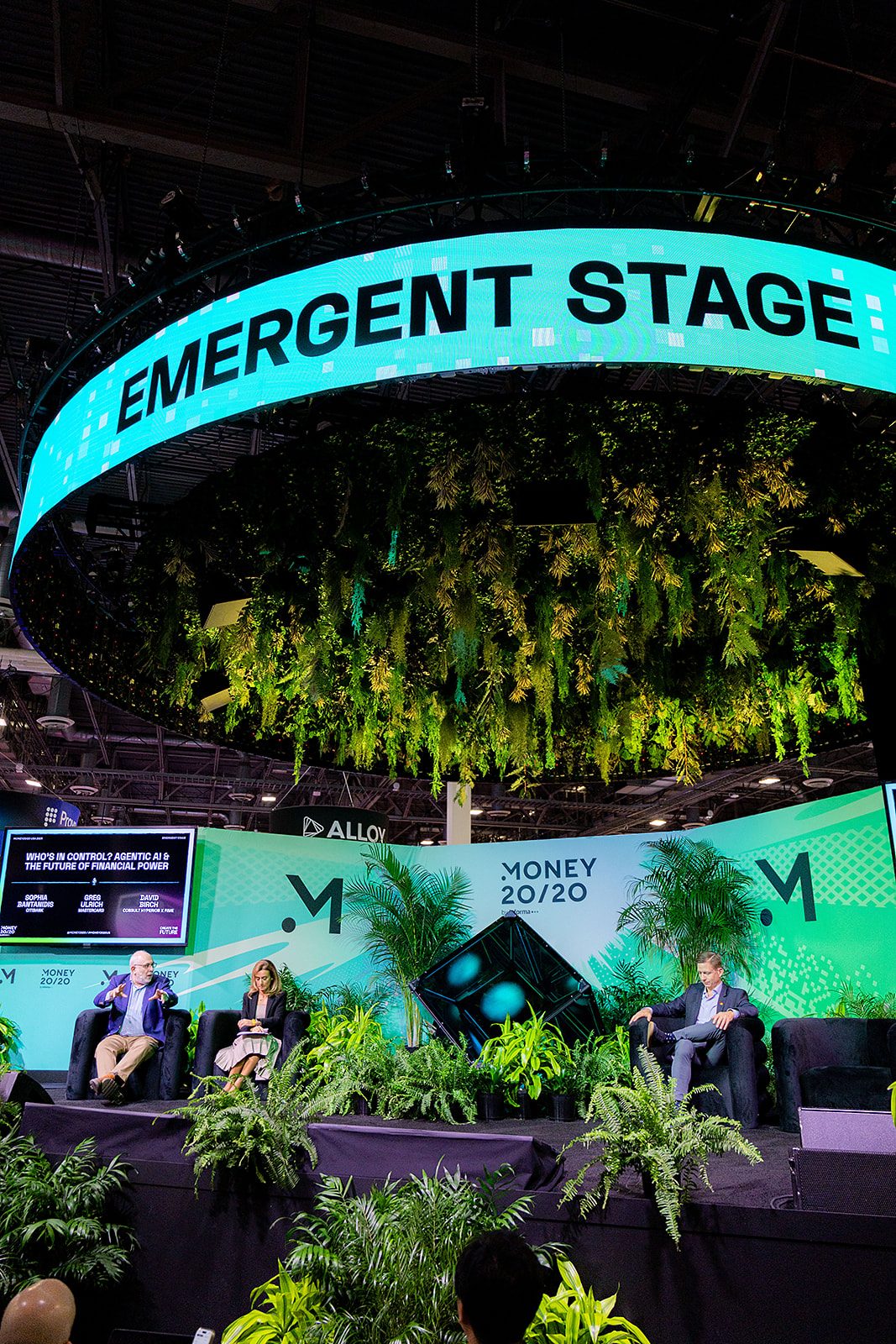 Emergent Stage panel under the turquoise ring and hanging plants