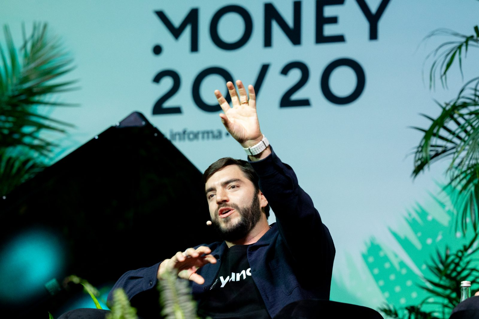 Emergent Stage speaker mid-gesture with the brand wall behind them