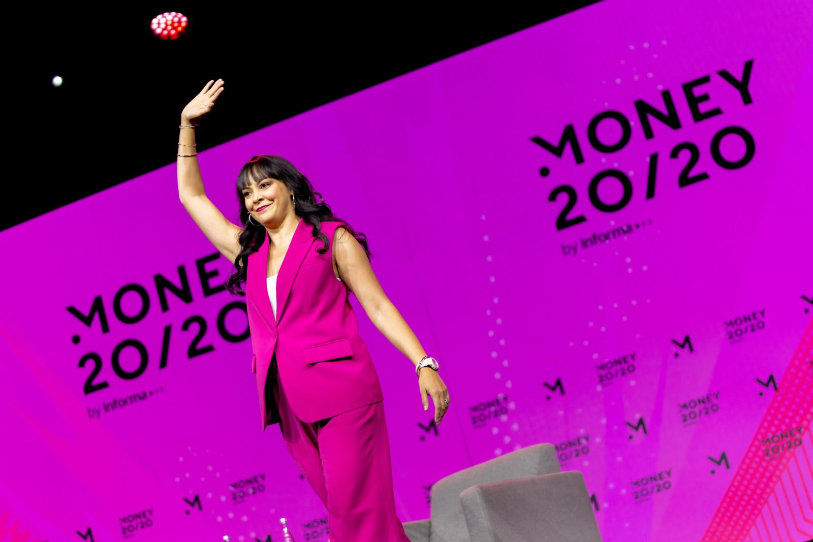 Speaker in a hot pink suit waving on the Money20/20 Main Stage