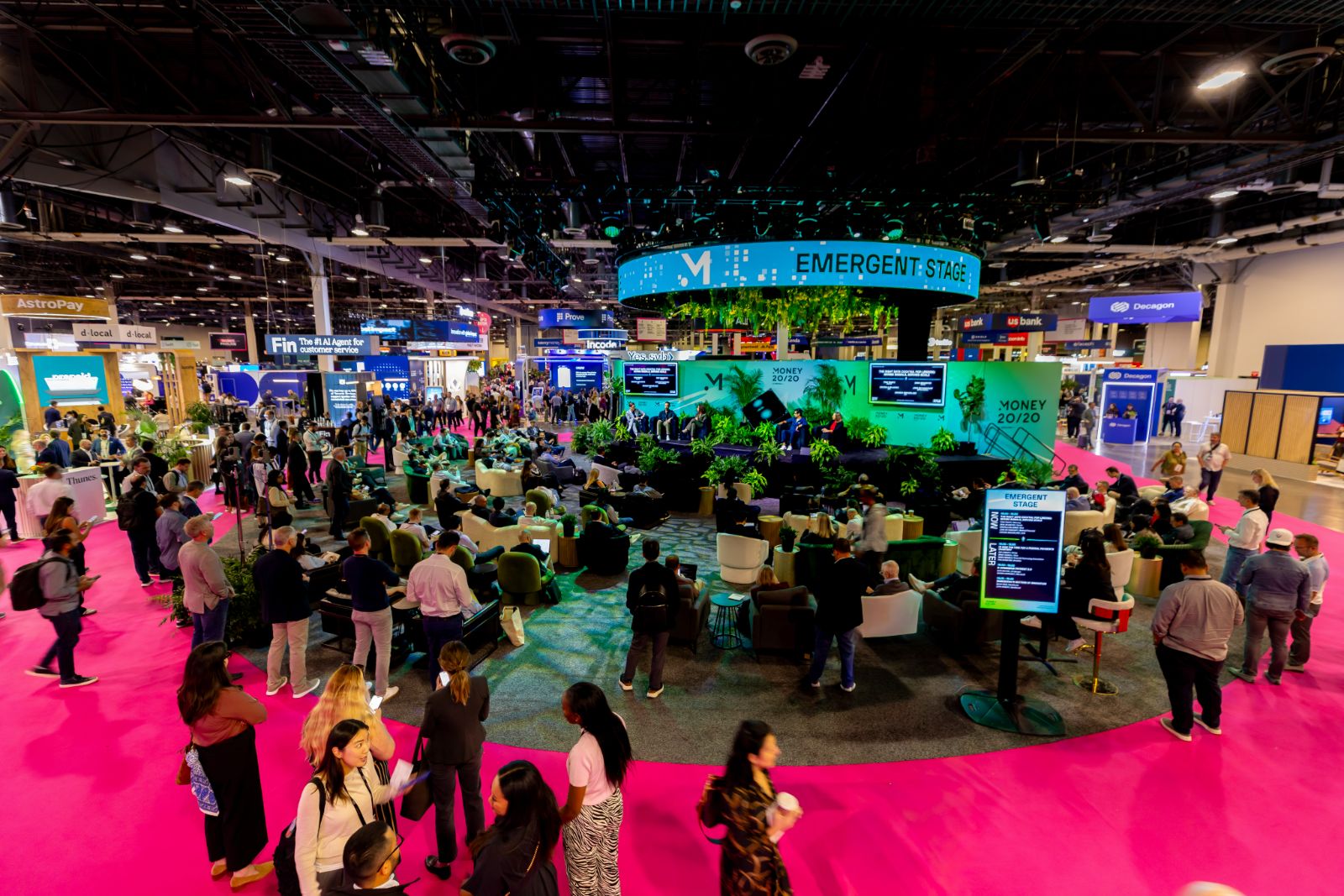 Hot pink expo floor, lounge seating in the round, and the Emergent Stage ring overhead at Money20/20 USA 2025
