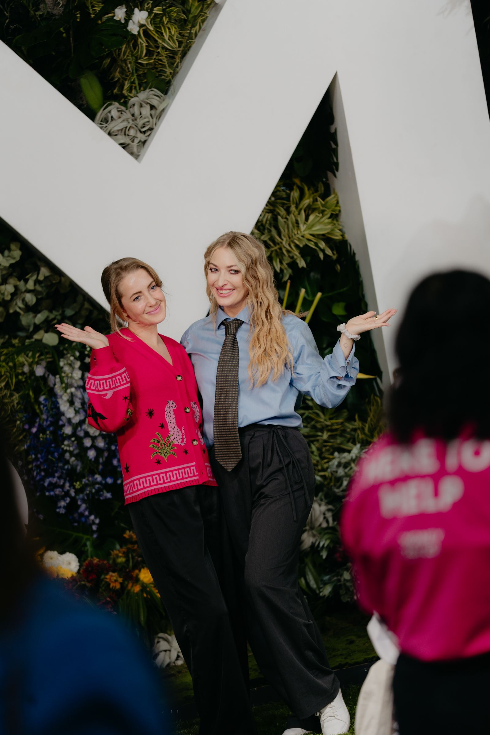 Two attendees posing playfully in front of the giant floral Money20/20 M installation