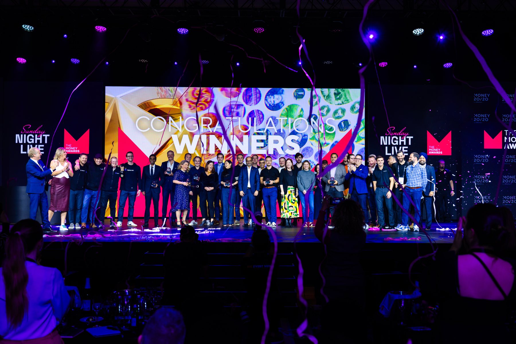 Money Awards winners holding their trophies on stage under confetti at Sunday Night Live